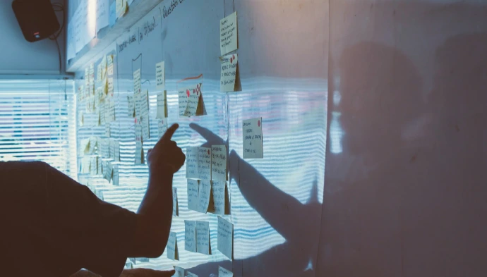 person pointing white paper on wall